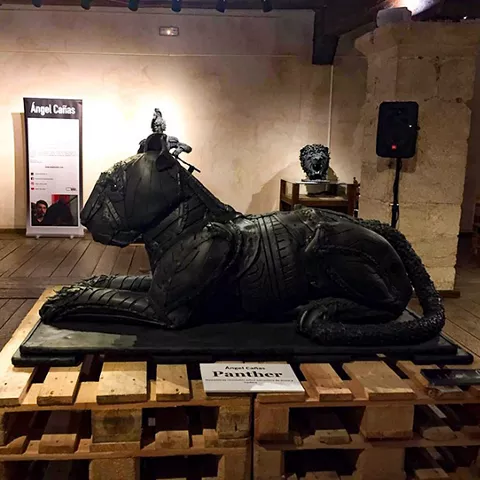 Escultura contemporánea expuesta en sala con muros de piedra