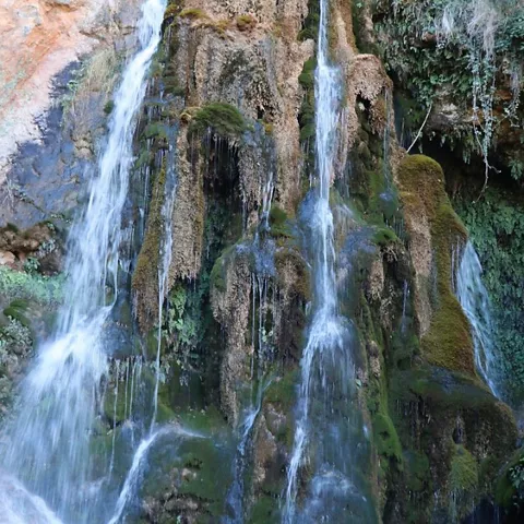 Cortina de agua deslizándose por roca cubierta de musgo