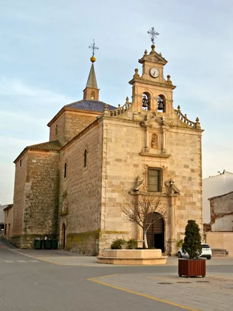 Fachada de ermita de piedra con torre y reloj.
