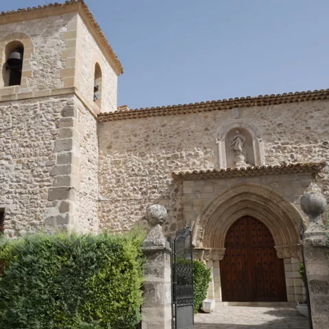 Fachada de piedra con torre y portada.