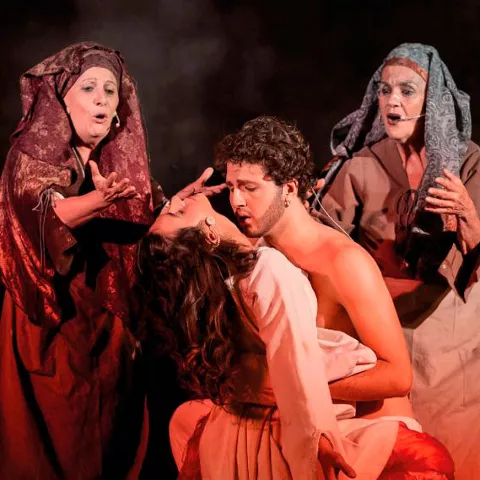 Escena teatral con figuras abrazadas bajo luces cálidas