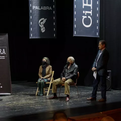 Coloquio en un escenario con varias personas sentadas y un moderador