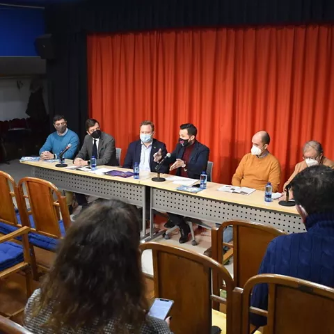 Mesa redonda con ponentes sentados frente a público en sala cerrada.