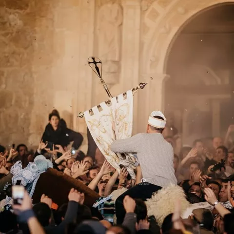 Estandarte elevado sobre un caballo rodeado de gente.