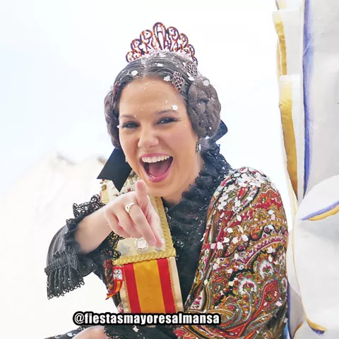 Mujer con traje tradicional señalando a cámara durante una celebración.