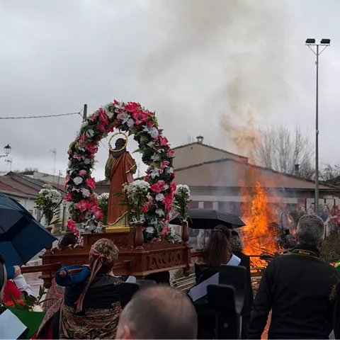 Imagen floral frente a hoguera durante celebración.