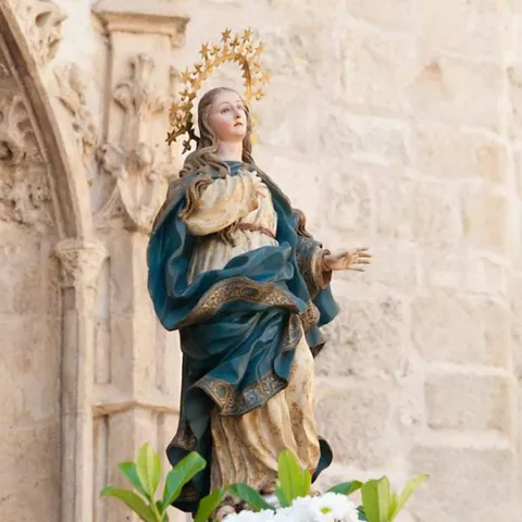 Imagen religiosa adornada con flores durante celebración popular