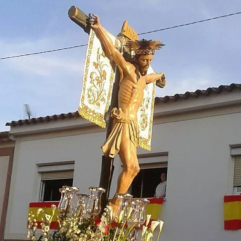 Paso procesional con imagen religiosa crucificada y adornos florales en la calle.