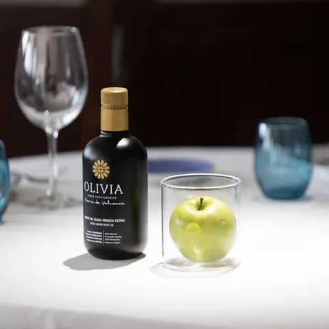 Botella de aceite de oliva y manzana verde en mesa