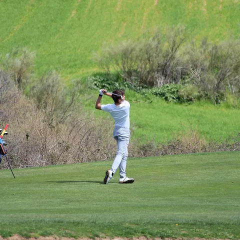 Green de tierra con bandera y colinas arboladas