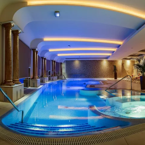 Piscina interior con iluminación ambiental y jacuzzi integrado.