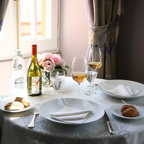 Mesa junto a la ventana con copas, pan y flores