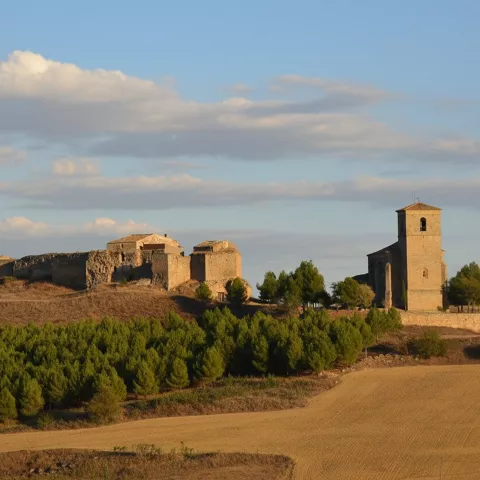 Conjunto fortificado y torre de piedra entre campos ondulados
