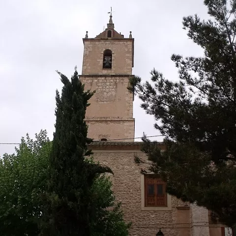 Torre campanario de piedra rodeada de árboles y vegetación.