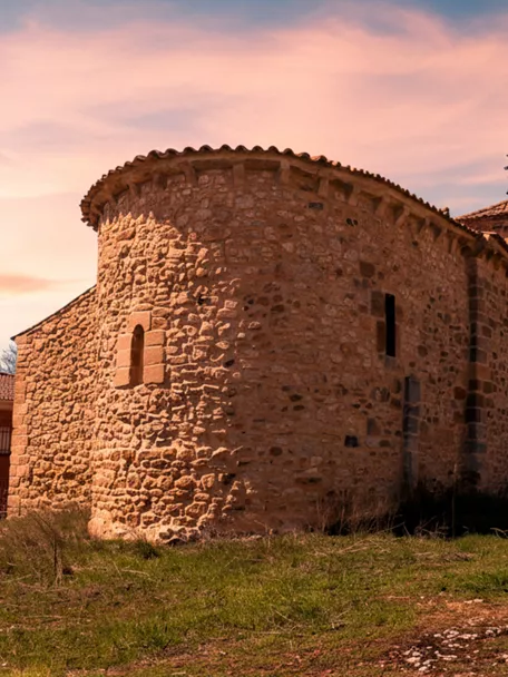 Fortaleza de piedra sobre una colina con campos agrícolas alrededor.
