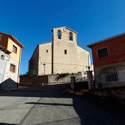 Iglesia de piedra vista desde una calle en pendiente entre casas.