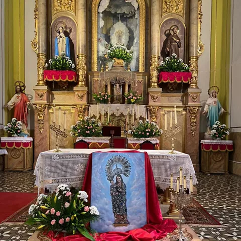 Retablo ornamentado con columnas y pintura central.