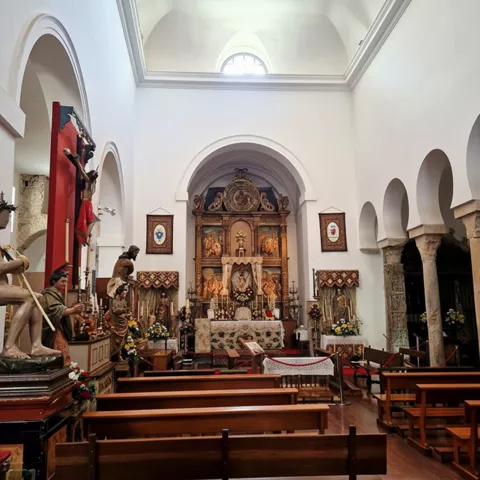 Vista del altar con imágenes religiosas y bancos alineados.
