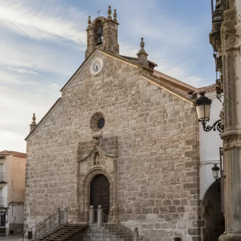 Vista lateral de iglesia de piedra con escalinata y portada principal.