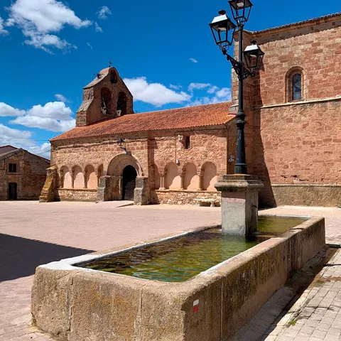 Plaza con fuente frente a iglesia histórica.