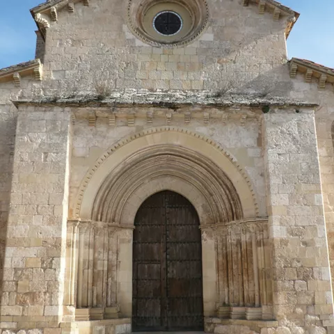 Portada de piedra con arquivoltas y puerta de madera.