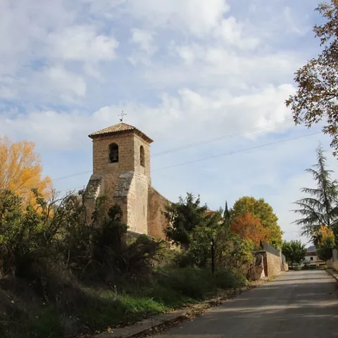 Iglesia rural junto a un camino entre árboles otoñales.