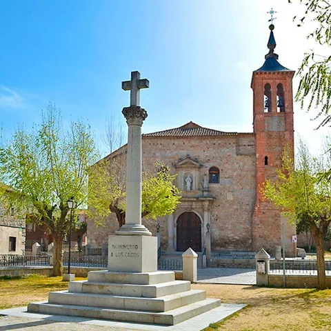 Iglesia de piedra con torre y cruz en la plaza