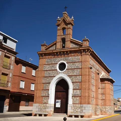 Iglesia de estilo tradicional con campanario y detalles decorativos en ladrillo bajo cielo despejado.