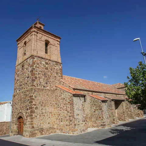 Iglesia de piedra con torre cuadrada y tejado de tejas.