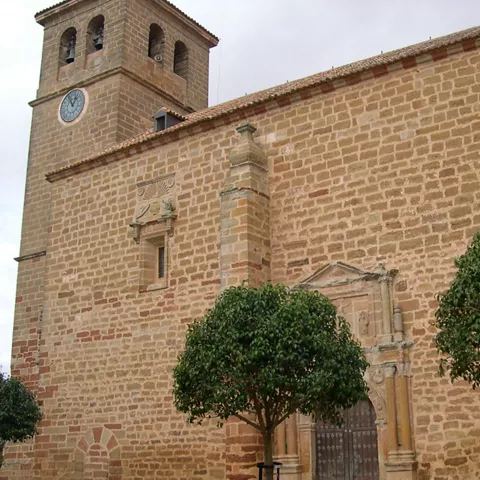 Iglesia de piedra con torre y reloj, vista lateral.