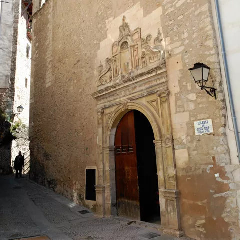 Fachada de piedra con portada tallada en calle estrecha.