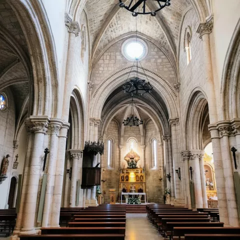 Interior con bóvedas apuntadas y altar iluminado.