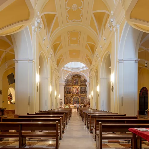 Interior de iglesia con nave central y retablo.