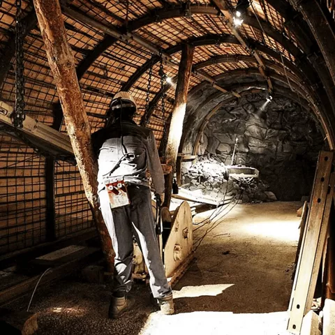 Recreación de galería minera subterránea con trabajador, estructuras de madera y maquinaria de extracción