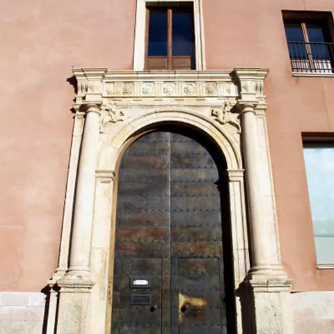 Portada de piedra con arco y escudo superior.