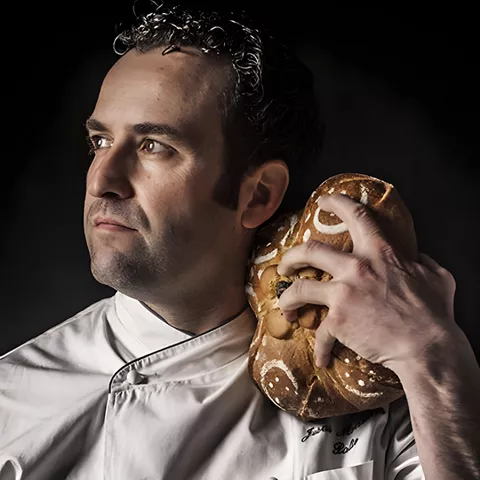 Retrato de cocinero con pan apoyado en el hombro