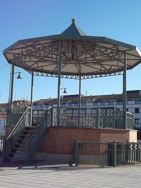 Kiosco elevado de estructura metálica en una plaza abierta.