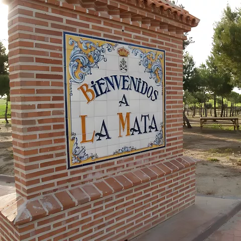 Monolito de bienvenida junto a zona arbolada