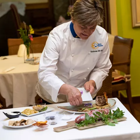 Cocinera emplatando plato gourmet en comedor acogedor