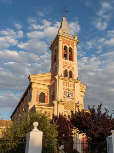 Iglesia de La Herrera con torre campanario de estilo tradicional, iluminada por la luz cálida del atardecer.
