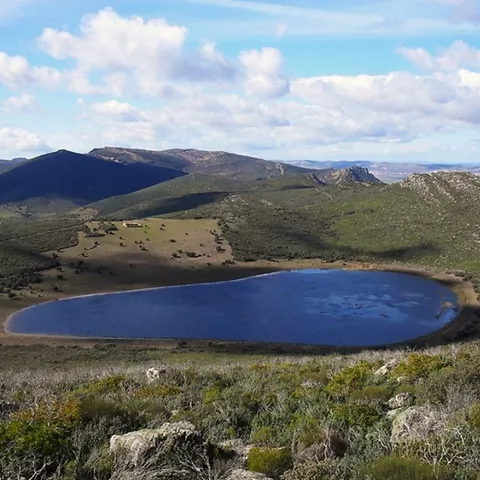 Paisaje volcánico con lámina de agua y matorral mediterráneo.