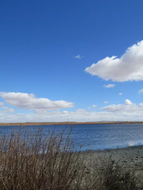 Panorámica de laguna con cielo azul y nubes dispersas