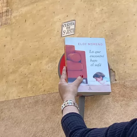 Libro sostenido frente a placa de calle histórica