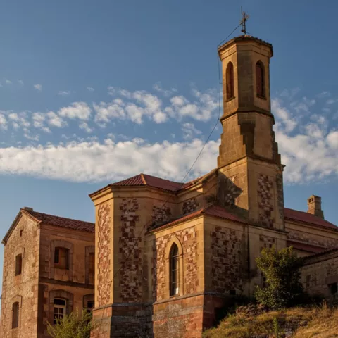 Iglesia de piedra con torre campanario sobre ladera