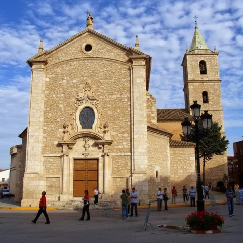 Iglesia parroquial de Madrigueras con fachada de piedra y torre campanario en la plaza principal del municipio.