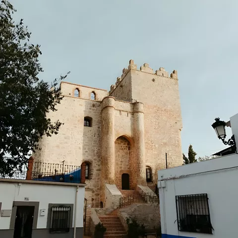 Castillo de piedra visto entre casas blancas