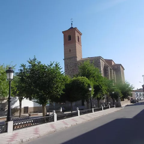 Iglesia de piedra al final de una calle arbolada