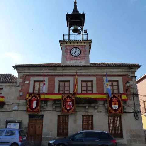 Ayuntamiento de piedra con reloj y banderas en la fachada
