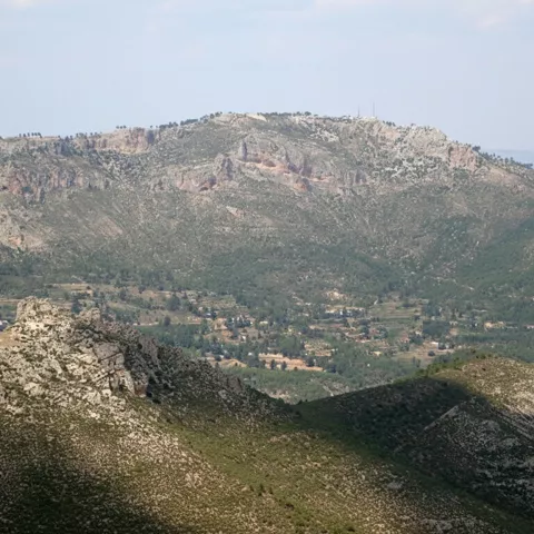 Vista panorámica de una montaña amplia con laderas verdes y rocosas.