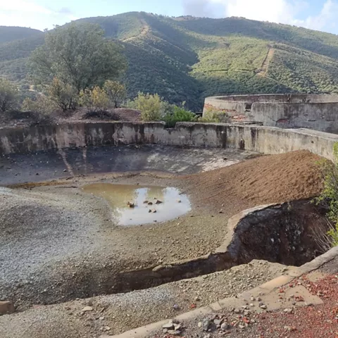 Estructura circular abandonada con restos de agua y vegetación